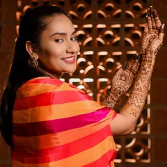 A gorgeous bride posing with her intricate mehendi. The henna beautifully complements her colorful outfit and the festive decor.