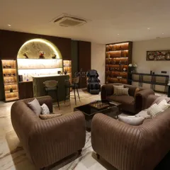 This wide view of the Harmony House bar area shows the cozy, customized sofas arranged for conversation, with the backlit bar display as a stunning backdrop.