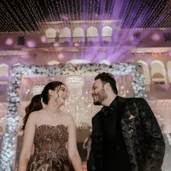 A candid glance between the couple under a sky of fairy lights. This shot captures the magic and romance of a Sangeet night at the Laxmi Vilas Palace.