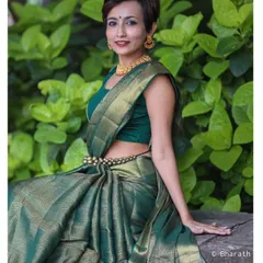 A full-length shot of the contemporary green saree look. The model's relaxed pose against a lush green background gives this traditional outfit a fresh, modern feel.