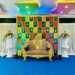 For a more colorful Mehendi or Sangeet function, we designed this backdrop with a grid of green, orange, and yellow fabric panels, decorated with hanging marigold strings. The ornate sofa completes the festive look.