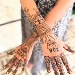 A playful and unique baby shower mehendi design. This one includes fun elements like "Boy" and "Girl" jhumkas, along with baby clothes and toy motifs, making it a fun guessing game for the family.
