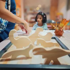 A young creator carefully inspects the wooden animal shapes from our DIY kit. We love sparking that initial moment of curiosity before the painting begins.
