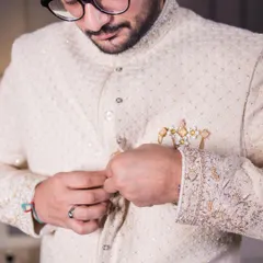A close-up shot of the groom getting ready, focusing on the details of his embroidered sherwani.