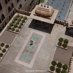 A drone's view captures the couple amidst the sprawling, symmetrical courtyards of a Jaipur palace, showcasing the scale of the venue.