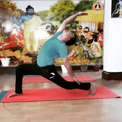 A student in Viparita Virabhadrasana (Reverse Warrior Pose). This posture builds strength in the legs while creating a beautiful side-body stretch, opening the space between the ribs.