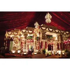 A wide view of our temple-style mandap, showcasing its majestic scale under a canopy of rich, red fabric and crystal chandeliers. This structure stands as the sacred focal point, blending cultural elegance with timeless craftsmanship.