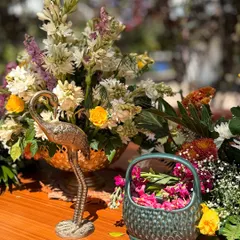 A close up of the festive details for a Holi celebration. A brass flamingo statue sits amongst fresh flowers and a bowl of pink gulal, blending elegant decor with traditional elements.