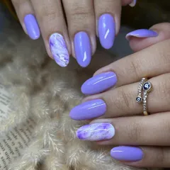 An elegant design featuring a solid lilac base with accent nails showcasing a purple and white marble effect. The soft, flowing pattern of the marble adds a touch of sophistication and visual interest.