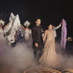 A grand Sangeet entry designed with intention. The couple enters through a haze of smoke, surrounded by performers with flowing fabrics, creating a dramatic and immersive start to the evening.