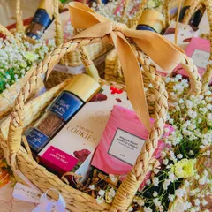 A dreamy hamper created with a theme of beiges, pastels, and florals. This small handwoven basket is filled with cookies, a scented candle, and other treats, making for a beautiful and elegant gift.