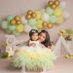 The sweet bond between sisters is a story I love to tell. Here, an older sister embraces her baby sibling during a milestone photoshoot, surrounded by soft pastel balloons and gentle light.