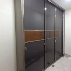 This sliding wardrobe features a modern design with grey and wood-finish panels, offering a space-saving solution that is both beautiful and functional.