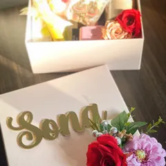 Gifting is an emotion. This personalized box features a stunning gold acrylic name tag and a vibrant floral bouquet, making the gift inside even more special.