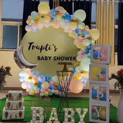 A lovely baby shower backdrop featuring a pastel balloon garland, a crescent moon foil balloon, and 'BABY' blocks for Trupti's celebration.