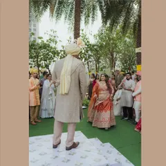 The bride walks towards the groom during the ceremony, a moment of beautiful anticipation. The outdoor setting with guests looking on creates a lovely, communal feel.