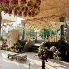 For a post-wedding vrattam function, I designed this serene Pichwai-themed decor in a farm setting. The space combines the rustic charm of a thatched roof with the elegance of traditional motifs and soft floral arrangements.