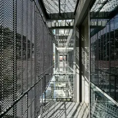 This is the facade of ICP Brunton Central, an adaptive reuse project where we gave an old building a new life. We designed a custom perforated and folded metal screen that acts as a filigree skin, filtering sunlight, reducing glare, and creating a delicate pattern of shadows on the walkways.