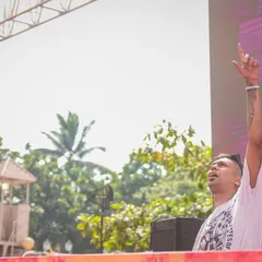 One hand for the mix, one for the sky. In the zone during a daytime festival set, connecting with the massive crowd in front of me.