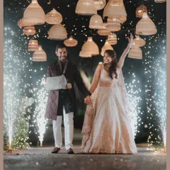 A grand entrance for a grand night. The couple makes their way into the Sangeet celebration, surrounded by sparklers and under a canopy of boho-chic lamps.