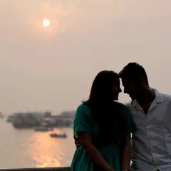 A romantic silhouette of a couple against the setting sun over the water. This style of pre-wedding photography creates a soft, intimate mood, focusing on the connection between the two of you.
