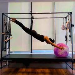 A graceful pose on the Cadillac using the push-through bar and a stability ball. This exercise combines spinal extension with core control, creating a long, elegant line.