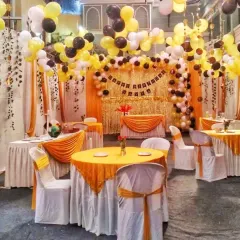 A complete birthday party hall decoration with a yellow, black, and white theme. I arranged the guest seating with matching table covers and set up a shimmering gold backdrop with a balloon arch.
