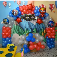 An Avengers-level party setup. This Marvel superhero theme features character balloons of Iron Man and Captain America, a city-scape backdrop, and a "Happy Birthday" banner.