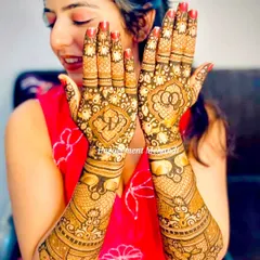 A happy bride-to-be with her engagement mehndi. The design includes her initials 'R' and 'K' inside a floral motif, a beautiful way to celebrate her union.