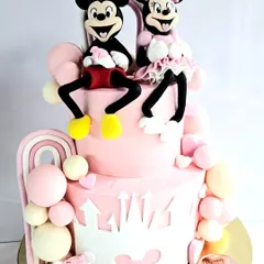 A classic theme that never gets old! This two-tiered Mickey and Minnie Mouse cake is perfect for a little one's birthday, featuring handcrafted, edible figures of the iconic duo sitting atop a pink castle-themed cake.