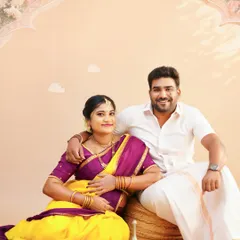 A classic portrait of a couple during their traditional maternity shoot. They are seated together in a studio setup designed for a timeless, cultural feel.