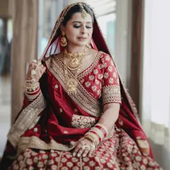 A quiet, seated portrait of the bride, capturing the intricate details of her jewelry and the rich fabric of her lehenga.
