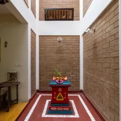 The central courtyard, a core feature of the home, housing a traditional Tulasi Katte against a backdrop of exposed brick, connecting the home to both nature and spirituality.