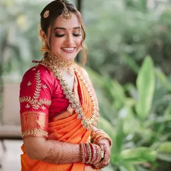 A smiling bride is the most beautiful bride. This close-up captures her joy and the flawless, balanced makeup that enhances her natural beauty without looking heavy. The orange and pink saree is a classic combination.
