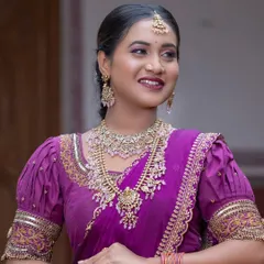 This bride has paired her purple saree with a lovely Victorian-style necklace set with pink beads.