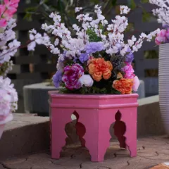 Even small details can create beautiful photo opportunities. This vibrant pink stool with a colorful floral arrangement adds a pop of color and elegance to a decor corner.