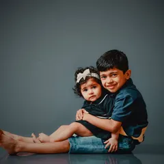 There's nothing like a big brother's hug. This sibling portrait on a simple grey background puts all the focus on the sweet, protective bond between them.