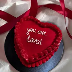 A simple, sweet message on a red heart-shaped bento cake: "you are loved." It's a small cake with a big heart, perfect for a personal gesture.