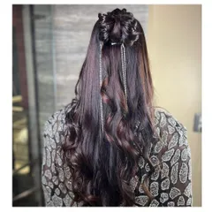 A chic and modern party hairstyle. This look features a half-up bun with long, flowing curls, accented with delicate silver hair chains for a touch of sparkle.