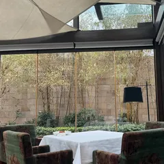 A quiet table framed by glass and grounded by wood, overlooking a serene bamboo garden. This is a sanctuary where you can escape the city and immerse yourself in the meal.