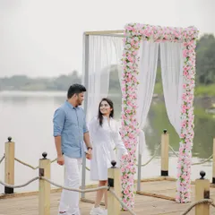 Walking towards their future. The couple holds hands as they approach a beautiful floral arch on a pier, the perfect setting for a romantic proposal.