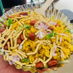 A bowl of our authentic Indori Poha. It's light, fluffy, and topped with crunchy peanuts, sev, and freshly chopped onions for that perfect texture and taste.