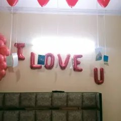 A romantic room decoration for a Valentine's gift or anniversary surprise. The "I LOVE U" foil balloons and photos hanging from heart-shaped balloons add a personal touch.