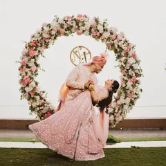 A fun and romantic dance pose in front of a circular floral arch. The bride's lehenga twirls beautifully, adding a sense of movement and joy to this stunning portrait.