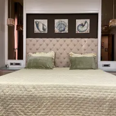 A cozy and classic master bedroom with a plush, button-tufted headboard. We flanked the bed with mirrors to make the room feel wider and reflect the light from the pendant lamps.