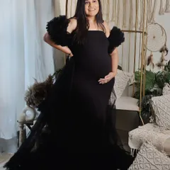 A powerful and confident pose in a striking black gown with tulle details. The mom-to-be stands proudly in our boho-chic studio corner, creating a look that is both elegant and modern.