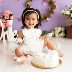 A happy moment from a butterfly-themed cake smash, showing a baby girl with a delightful, frosting-covered smile.