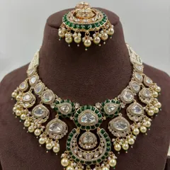 A complete bridal solution, this rental set features a heavy kundan and moissanite necklace with a matching maang tikka and statement chandbali earrings. The green enamel and pearl details add a classic touch.