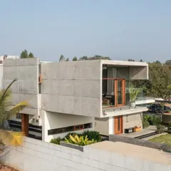 The side elevation of The Quarry House reveals a complex arrangement of stacked and cantilevered volumes. The design uses exposed concrete to create a raw, monolithic aesthetic that is softened by the lush tropical planting.