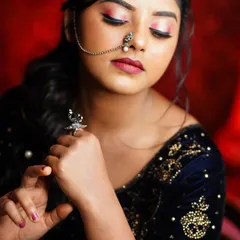 This is a powerful studio portrait designed for a model's portfolio. The focus is on the unique silver jewelry, especially the nose-to-ear chain, and the model's soft, elegant pose against a rich, dark background.